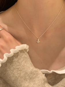 Close-up of golden butterfly pendant necklace worn by a model with an elegant knit top