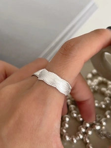 Dettaglio anello in argento S925 con trama spazzolata e bordo ondulato con perline