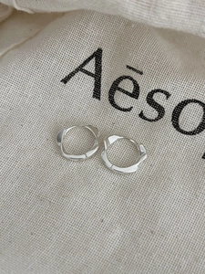 Détail de créoles irrégulières ondulées en argent sterling 925 sur un tissu texturé