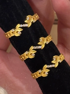 Detail of three vintage gold leaf rings with zircons on a black display stand
