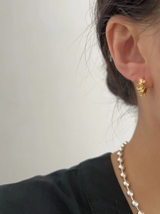 Vue détaillée de boucles d'oreilles fleurs dorées avec petits diamants sur un mannequin
