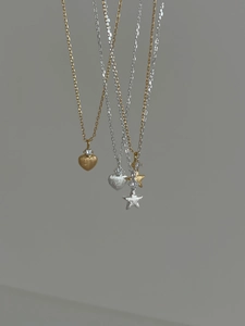Détail des pendentifs cœur et étoile avec finitions brossées or et argent sur fines chaînes