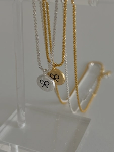 Detailed close-up of brushed silver and gold round pendants with black bow engravings