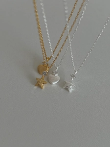 Détail macro des pendentifs étoile dorée brossée et cœur argenté avec micro-incrustations