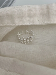 Vue macro de la bague tressée en argent S925 sur un tissu en lin texturé