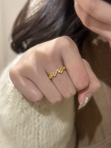 Detail of vintage gold leaf ring with sparkling zircons worn on finger with sweater