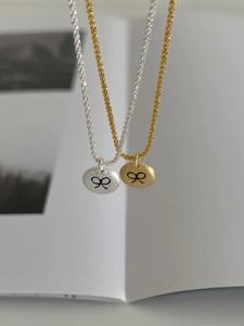 Detailed view of matte silver and gold coin necklaces with black bow engraving