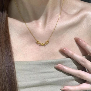 Collier à fleurs dorées avec cristaux roses porté sur la clavicule du modèle