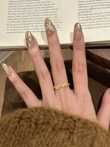 Close-up of a gold vintage leaf ring with zircon stones worn on finger over a book