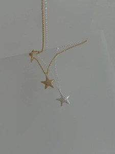 Detail of silver and gold starfish pendant necklaces featuring zircon inlays and fine chains