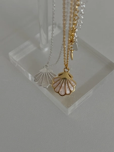 Détail de colliers pendentifs en forme de coquille dorés et argentés sur support