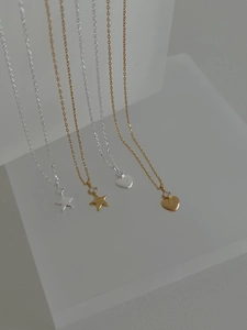 Détail de pendentifs étoile et cœur en métal brossé ornés de zircons brillants
