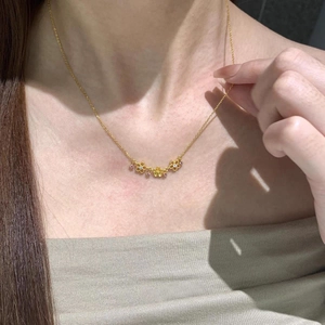 Collier doré avec cinq pendentifs fleurs évidées et cristaux roses sur un mannequin