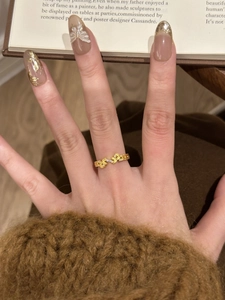 Detail of vintage gold leaf ring with zircon accents worn against a cozy knit background