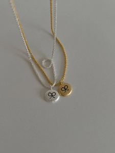 Macro detail of silver and gold brushed disc pendants with delicate bow pattern engraving