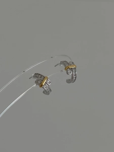 Detail of C-shaped 925 sterling silver hoop earrings with gold band and pavé zircons