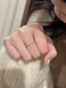 Detailed close-up of a vintage gold leaf ring with cubic zirconia on a white knit fabric