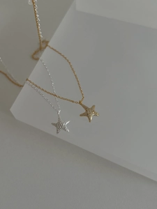 Detail of star pendants in gold and silver finish with sparkling pave-set zircons