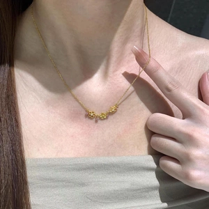 Détail du collier cœur doré avec trois pendentifs floraux et pierres roses sur le cou