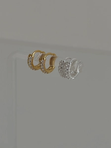 Détail macro de boucles d'oreilles créoles or et argent serties de zircones cubiques