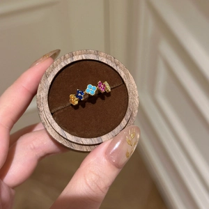 Close-up of golden ring featuring five colorful clover flowers set with vibrant crystals