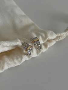 Detail of 925 sterling silver C-shaped hoop earrings with pave diamonds and gold bar