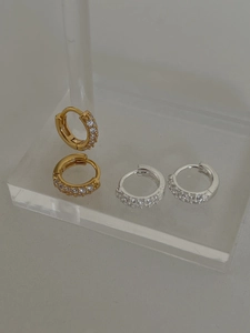 Détail des boucles d'oreilles huggies en argent 925 avec zirconiums dorés et argentés