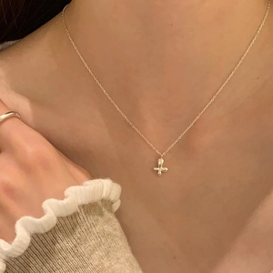 Minimalist gold cross pendant necklace and ring set worn by model for an elegant look