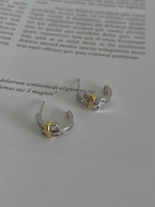 Macro detail of 925 sterling silver C-shaped earrings with inlaid zircons and gold accent