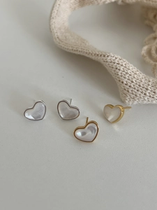Detailed view of heart-shaped earrings with mother-of-pearl inlay in gold and silver frames