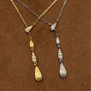 Dettaglio della collana con frange a goccia, texture in metallo spazzolato e micro diamanti