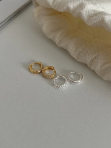 Gros plan de boucles d'oreilles huggies dorées et argentées pavées de zircons