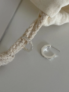 Macro shot of silver 925 octagonal hoop earrings with diamond pavé and rhombic texture
