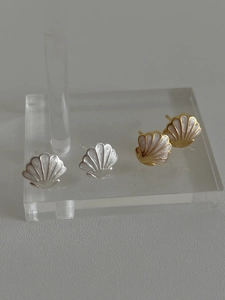 Détail de boucles d'oreilles coquillages en argent et or avec texture en émail blanc