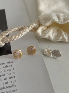 Gros plan de boucles d'oreilles coquillage avec cadres dorés et argentés sur un magazine