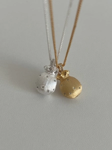 Makro-Detail von Gold- und Silber-Glücksbeutel-Halsketten mit gebürstetem Metall und Kristallen