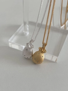 Detail von silbernen und goldenen Glücksbeutel-Anhängern mit mattem Finish und Steinen