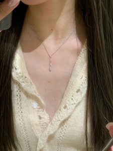 Dettaglio della collana in oro spazzolato con tre pendenti a goccia d'acqua lineari