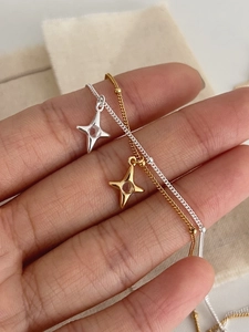 Close-up of S925 sterling silver star necklaces in gold and silver finishes on a hand