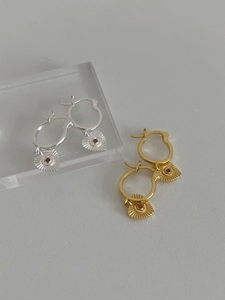 Dettaglio di orecchini a cuore in argento S925 e oro con zircone rosso e texture cuore
