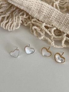 Macro view of heart-shaped mother of pearl earrings in gold and silver finish