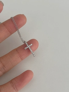 Close-up of a silver 925 cross necklace with cubic zirconia pavé on a thin O-chain
