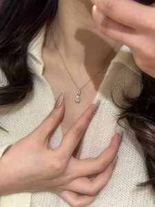 Close-up of a silver-toned necklace featuring two sparkling pear-shaped teardrop stones