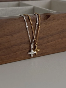 Detailed view of silver and gold star pendants with zircons on a walnut jewelry box