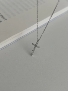 Close-up of a 925 sterling silver cross necklace with pavé zircon stones on open book