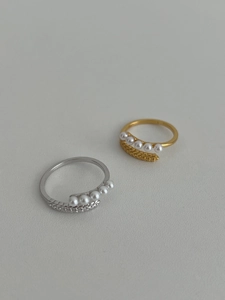 Dettaglio degli anelli a spiga di grano oro e argento con eleganti perle bianche