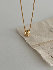 Macro detail of gold cylinder pendant with star engraving and small diamond on chain