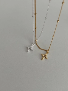 Close-up of gold and silver S925 necklaces featuring minimalist four-point star pendants