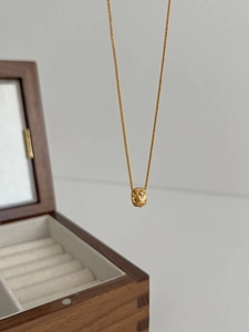 Close-up of gold cylinder pendant with frosted finish and sparkling zircon detail