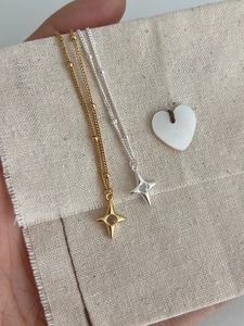 Detail of S925 sterling silver star pendants with zircon inlay on beige linen background